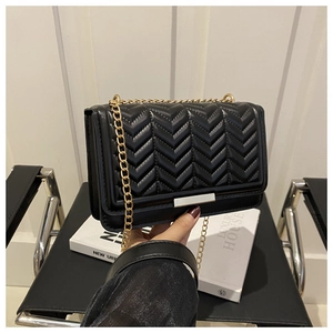 Close-up of black quilted leather crossbody bag with elegant gold chain and metal clasp