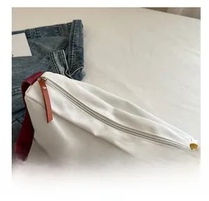 Detail der weißen Canvas-Umhängetasche mit Reißverschluss und buntem gewebtem Gurt