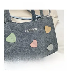 Detail view of denim blue handbag featuring white FASHION text and colorful heart patches