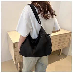 Large black nylon tote bag with wide strap worn by model for daily commuting style