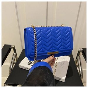 Detail of royal blue quilted leather texture with gold metal bar and chain strap