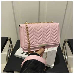 Detail of pink quilted leather crossbody bag with elegant V-stitch and gold chain strap