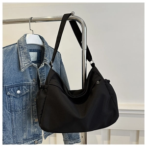 Detail of black canvas bucket bag featuring side zip pockets and drawstring ruching
