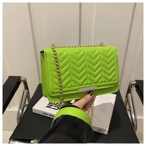 Detail view of neon green leather crossbody bag with V-quilted texture and gold chain strap