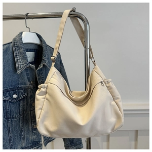 Close-up of cream canvas hobo bag with side pleats and adjustable silver buckle strap