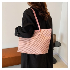Pink tote bag with geometric patterns shown on a model wearing a black coat