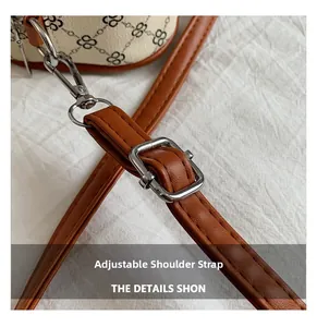 Detail of adjustable brown leather shoulder strap with silver buckle on clover pattern bag