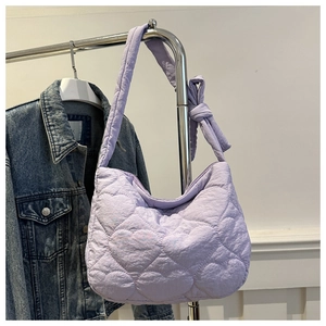 Détail du sac matelassé lavande avec motif cœur et nœud élégant sur la bandoulière large