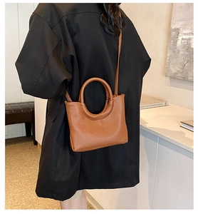 Detailed view of the caramel brown textured leather handbag with a circular top handle