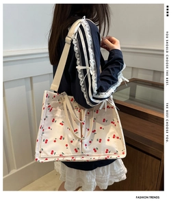 Detailed view of canvas tote bag with red cherry prints and front utility pockets