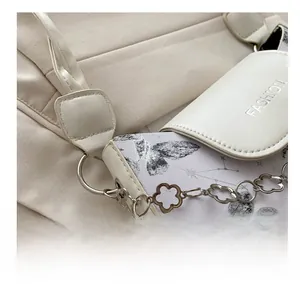 Detail of silver flower chain and FASHION embossing on butterfly print shoulder bag