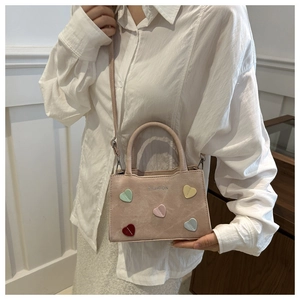 Pink crossbody bag with colorful heart patches and fashion print worn by a model