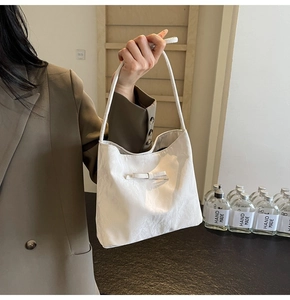Detailed side view of white tote bag featuring wrinkled texture and bow decoration