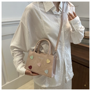 Close-up of pink tote bag with colorful heart patches and silver fashion lettering