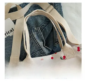 Close-up of a white canvas tote bag with cherry prints and thick woven handles