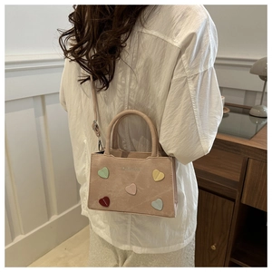 Detail of light beige tote bag with colorful heart patches and fashion print