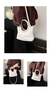 Close-up of white lychee-patterned handbag with round handle and adjustable strap