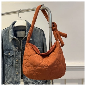 Détail du sac matelassé cœur caramel avec un nœud décoratif élégant sur la bandoulière