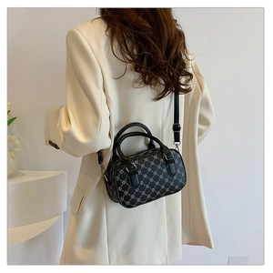 Model wearing a black Boston bag with silver clover patterns and a white blazer