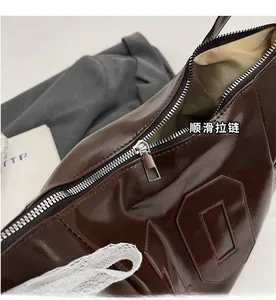 Détail de la fermeture éclair argentée et cuir marron foncé brillant du grand sac