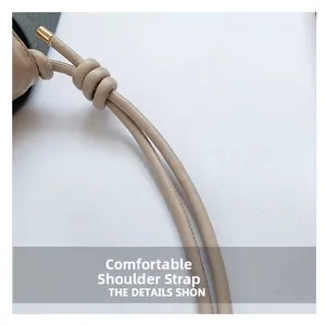 Detail of the soft beige leather shoulder strap with golden metal caps and decorative knot