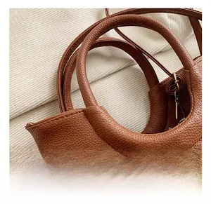 Close-up of the pebbled leather texture and rounded handle of this brown handbag