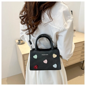 Detail of black crossbody bag with colorful heart patches and Fashion text on model