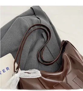 Détail du sac cabas marron brillant avec motifs géométriques et ruban dentelle sur veste
