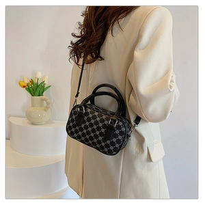 Chic black boston bag with white floral pattern worn by a model in a minimalist setting