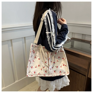Detail of canvas tote bag with cherry print featuring front pockets and cotton handles