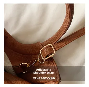 Macro shot of adjustable brown leather shoulder strap with gold metal buckle and lobster clasp