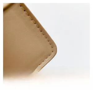 Detail view of smooth beige leather underarm bag featuring precision stitching and matte texture