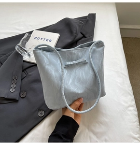 Detail of light blue wrinkled marble texture tote bag with a bow on white bedding