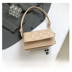 Detail of beige quilted shoulder bag with unique knot handle design and soft leather texture