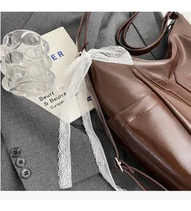 Détail du sac à main marron en similicuir avec poche latérale et décoration en dentelle blanche