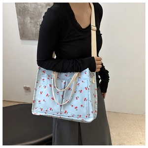 Detail of light blue canvas tote bag featuring red cherry prints and outer pockets