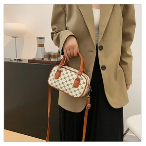 Close-up of retro small square crossbody bag with clover print and brown leather handles