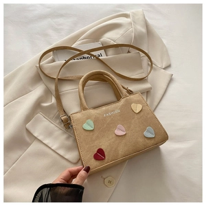 Detail of light brown corduroy handbag with colorful heart patches and fashion text logo