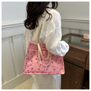 Detail of pink canvas tote with cherry print, dual front pockets and adjustable strap