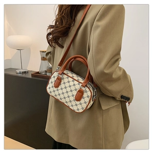 Woman in khaki suit modeling a retro patterned shoulder bag with brown leather handles