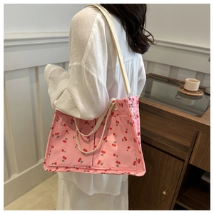 Detail of pink canvas tote bag with cherry prints featuring large front pockets