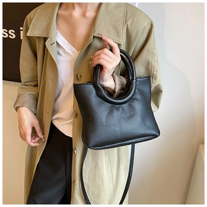Detailed view of black litchi grain tote bag with unique circular handle and long strap