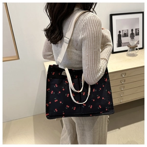 Detailed view of canvas tote bag with cherry print and adjustable wide strap on model