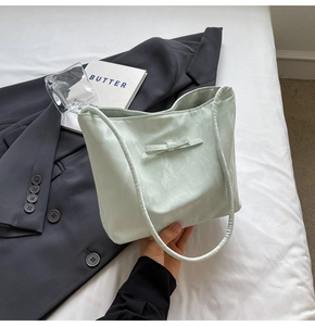 Detail of mint green tote bag with bow accent held against an aesthetic backdrop