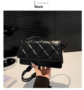 Detail of black quilted shoulder bag featuring triangular stitching and metal side hardware
