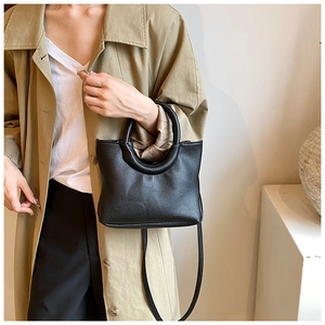 Close-up of a black lychee texture leather handbag with stylish circular top handle