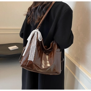 Détail du sac cabas en cuir verni marron avec nœud en dentelle blanche et broderie 10