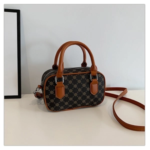 Detail view of mini Boston bag with golden clover pattern and caramel leather handles