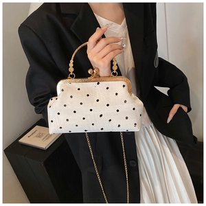 Close-up of vintage shell bag with black polka dots, gold ring handle and chain strap