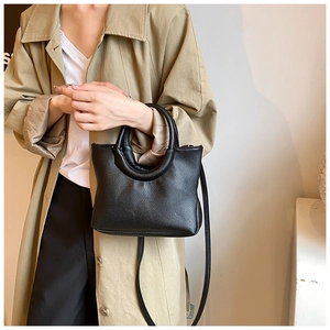 Close-up of black litchi pattern leather handbag featuring elegant round top handle